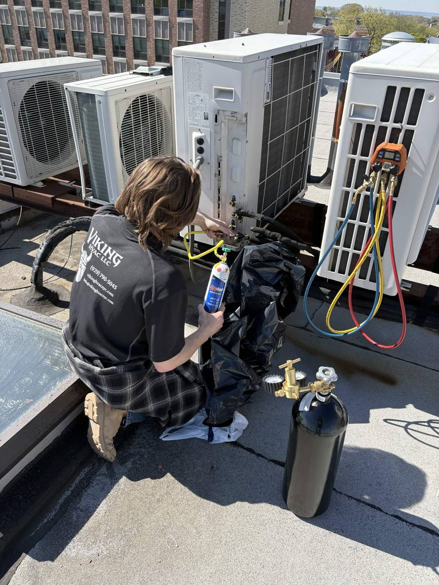 Technician performing line flush and commissioning work on rooftop HVAC equipment