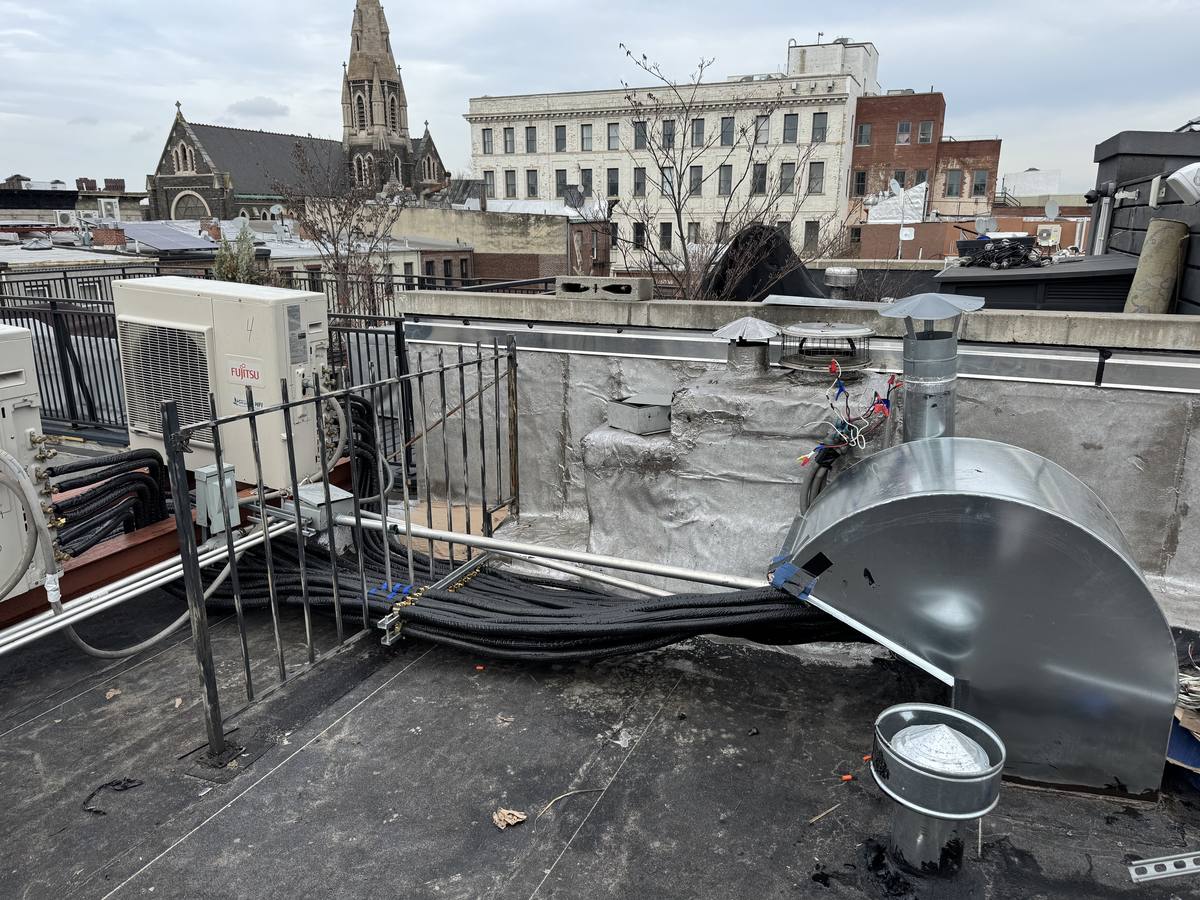 Rooftop heat pump equipment on a Brooklyn brownstone with nearby historic buildings